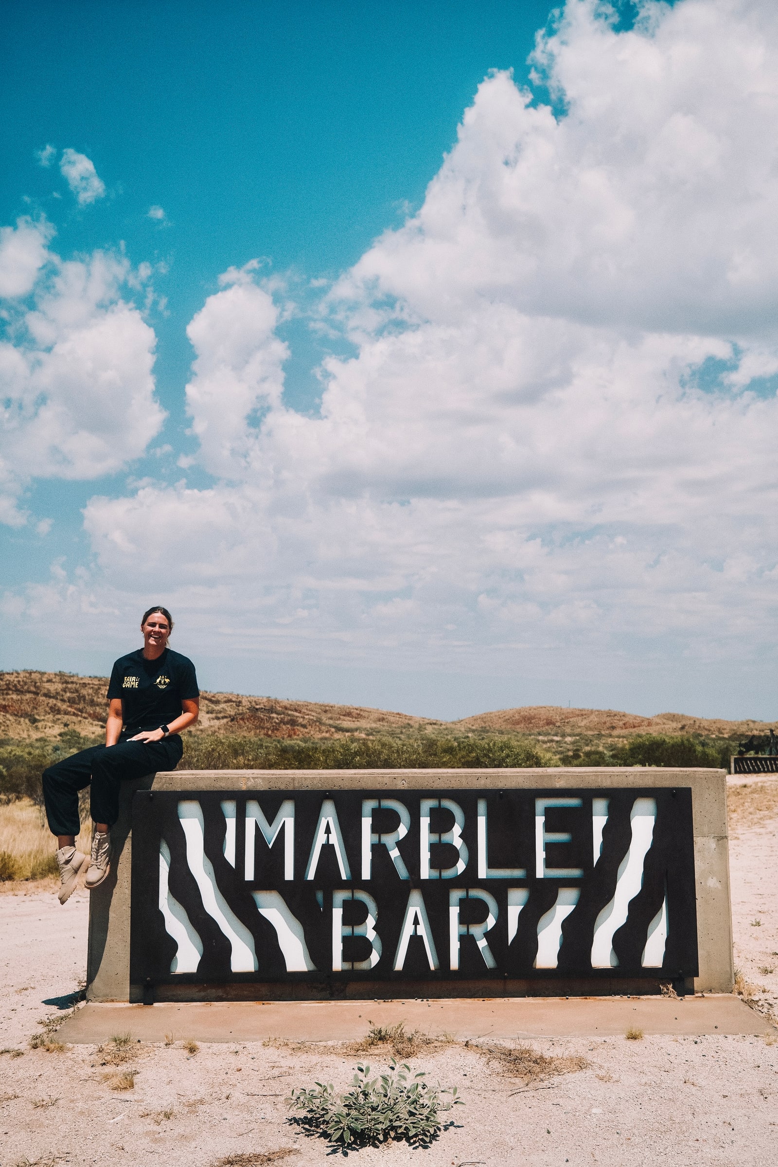 Shayna Jack sitting on the Marble Bar town sign in the Pilbara outback.