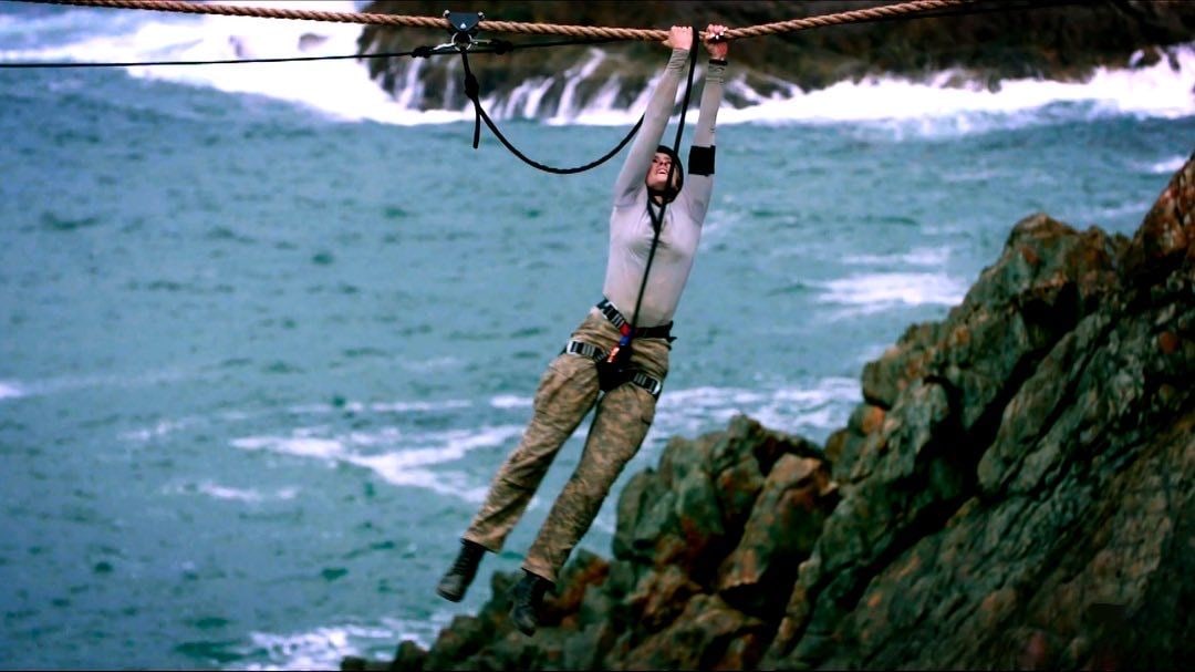 Shayna Jack hanging from a rope traverse above the sea on SAS Australia.