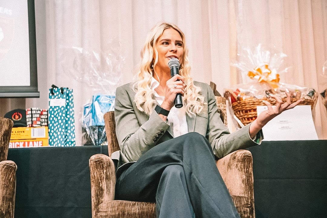 Shayna Jack seated in an armchair, speaking into a microphone at an event.