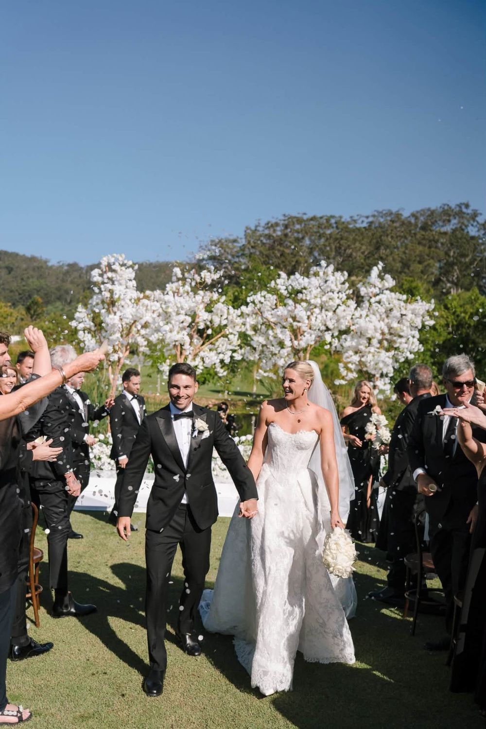 Shayna and Joel walk back down the aisle hand in hand as guests throw confetti.